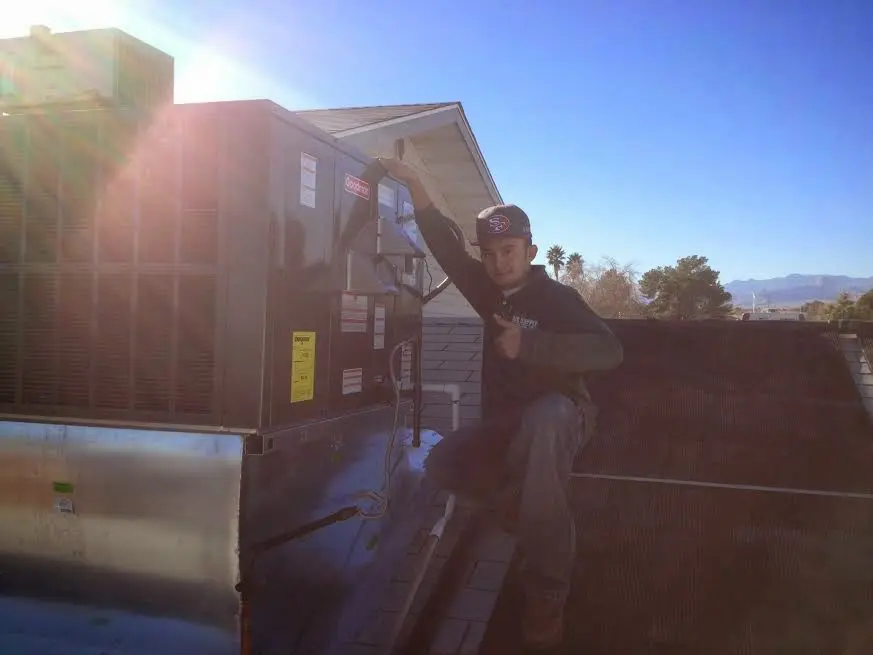 HVAC technician performing AC Tune-Up on a rooftop unit in Vernon